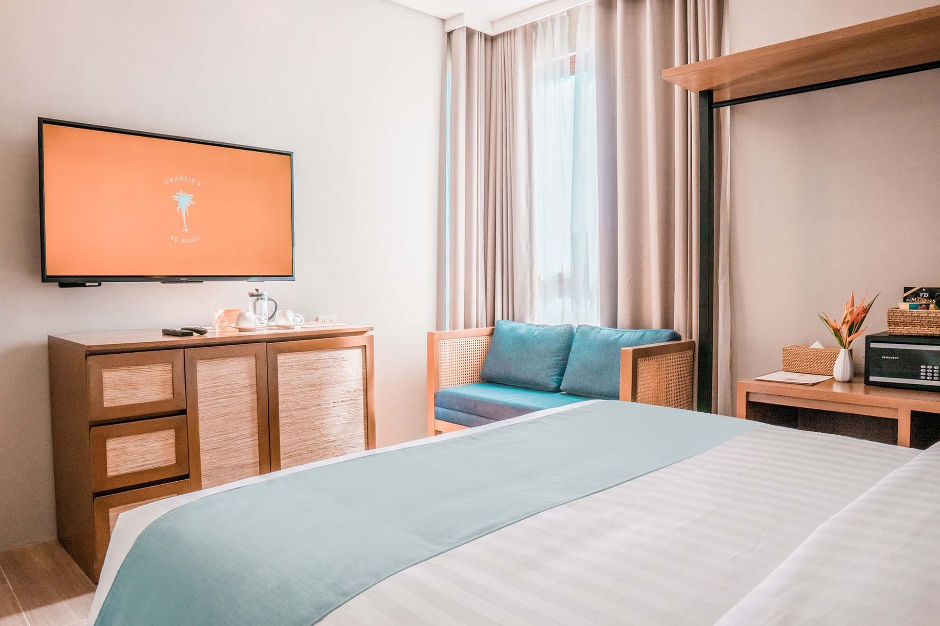 Hotel room featuring king bed with teal runner, flat-screen TV and comfortable seating area