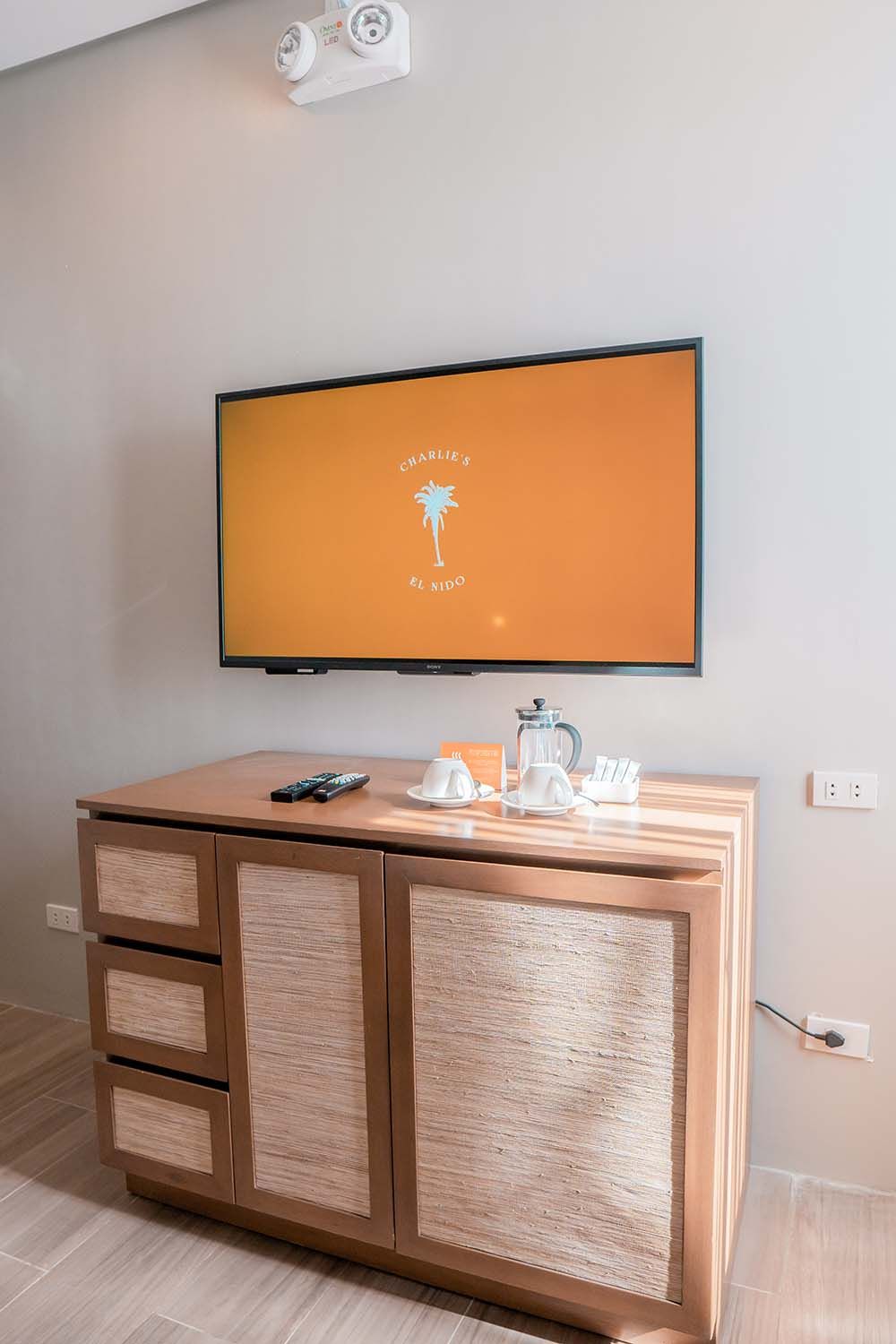 Sleek entertainment setup with flatscreen TV displaying a palm tree logo and wooden console