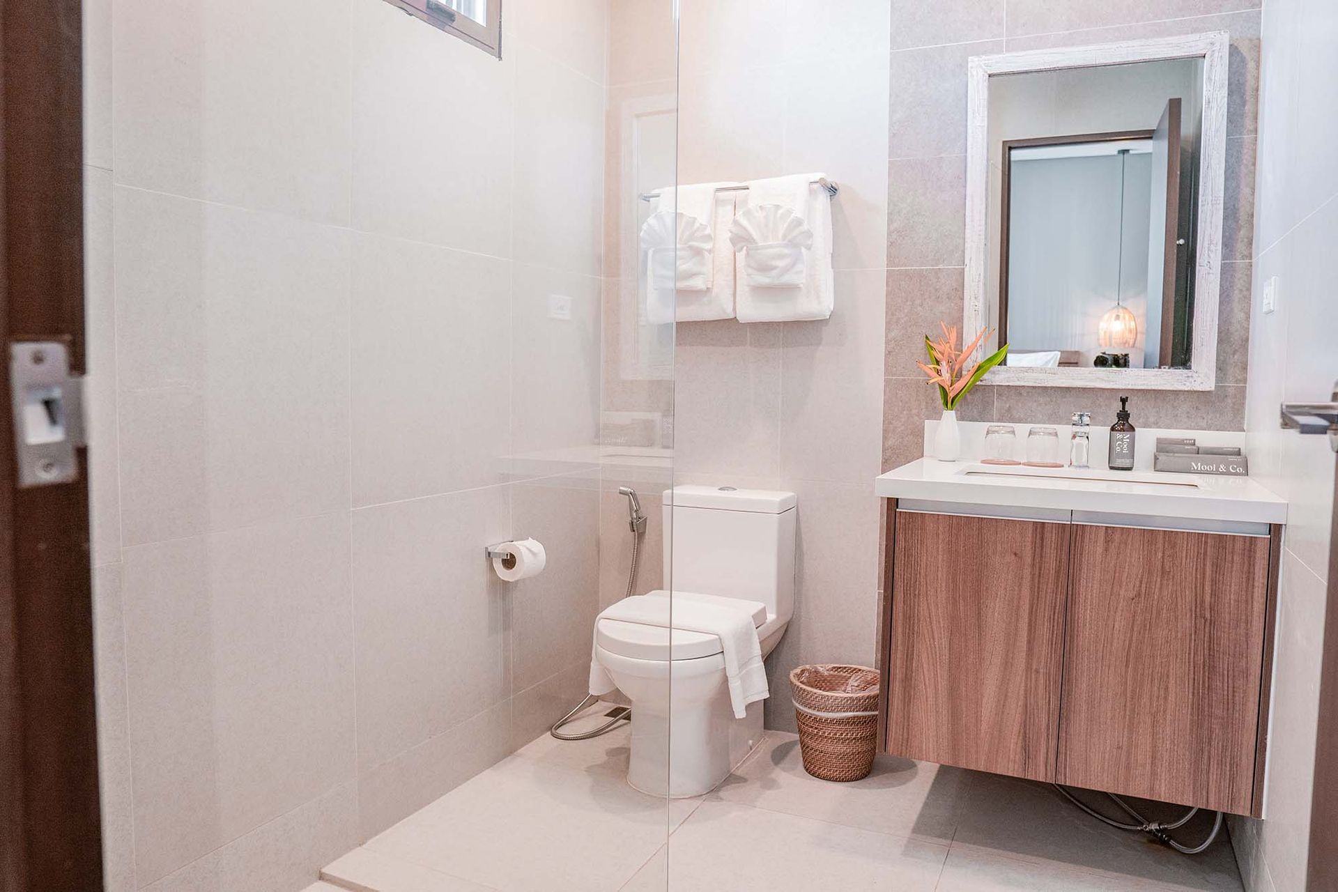 Modern bathroom with wooden vanity, white fixtures and woven basket for a tropical feel