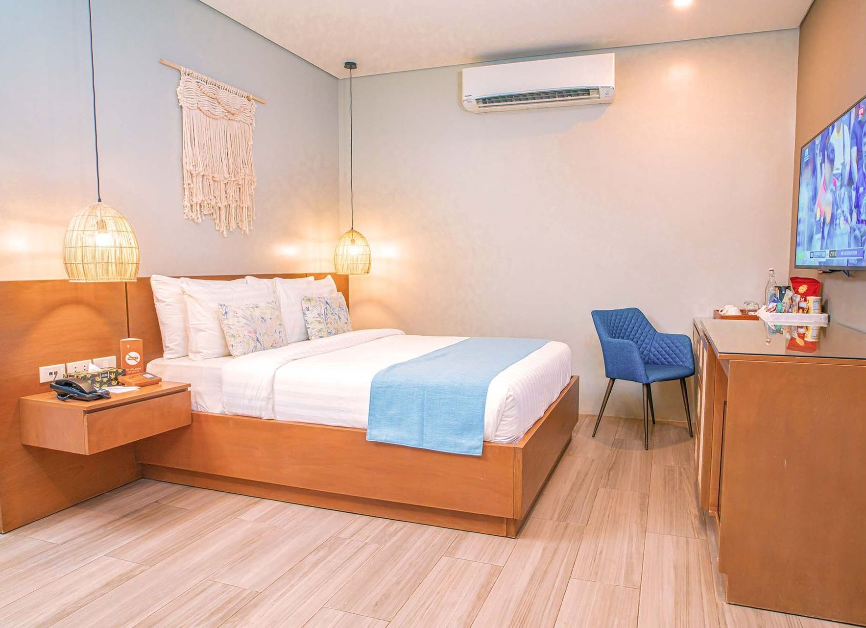 Cozy air-conditioned room with single bed, blue runner, desk area and wall-mounted TV.