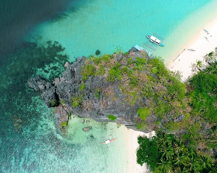 Bird's eye view of a secluded beach and coral reefs at an El Nido resort island in Palawan