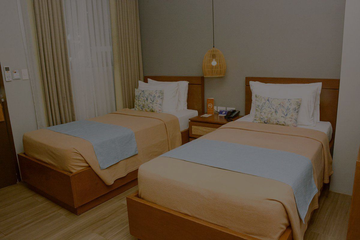 A hotel room with two twin beds and a nightstand.