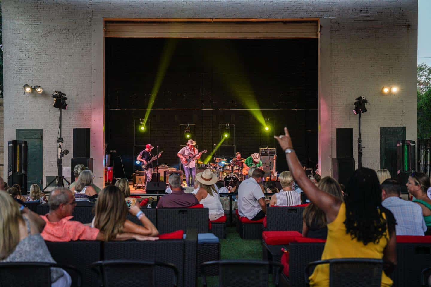 A group of people are sitting in front of a stage watching a concert.