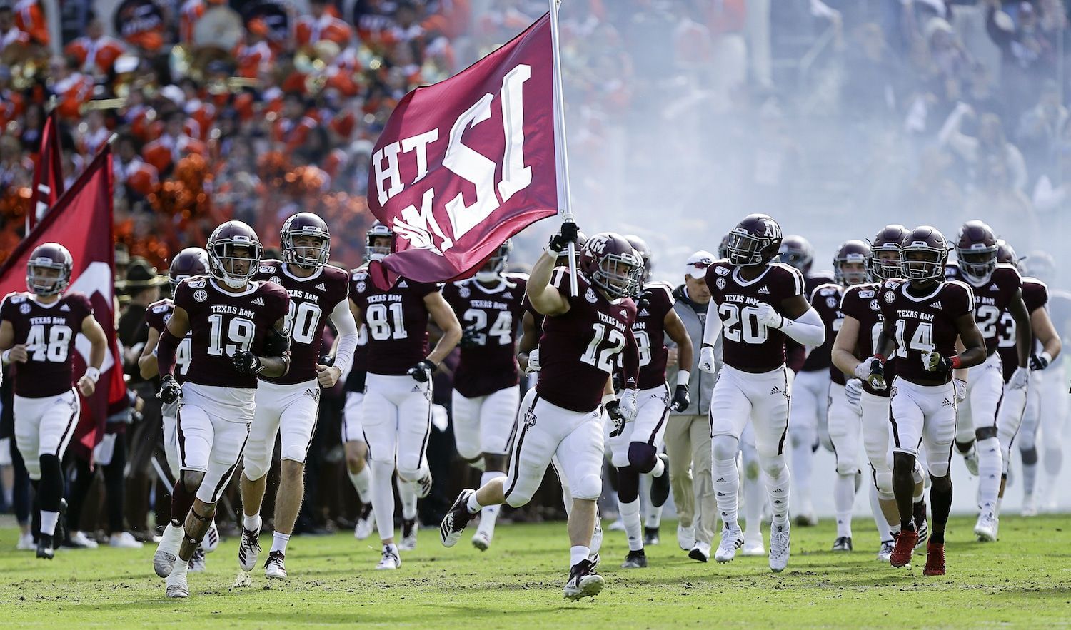A football team is running on the field with a flag that says tsl