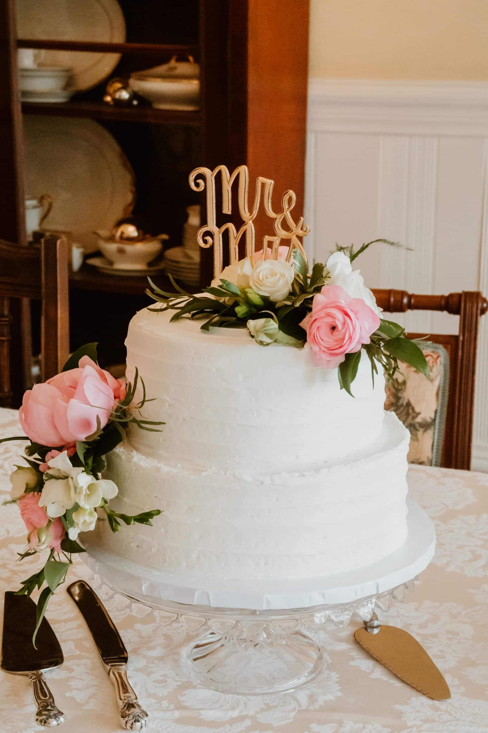 A wedding cake is sitting on a table with flowers and a cake topper.