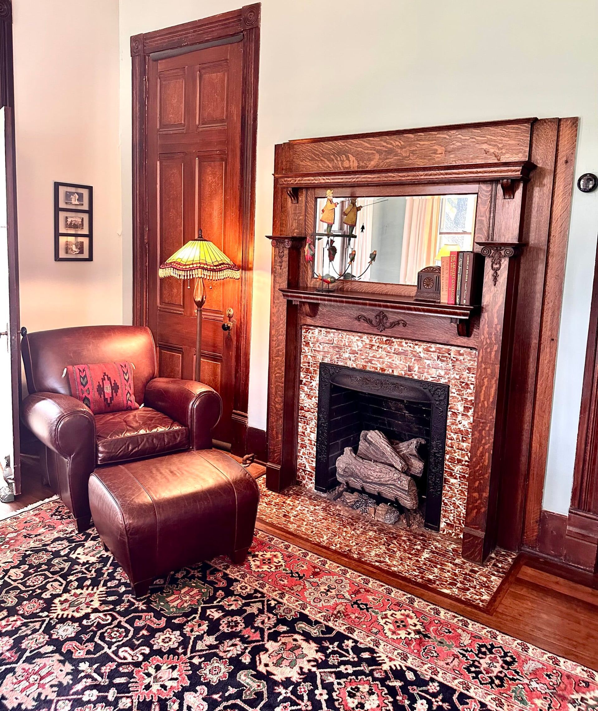 A living room with a fireplace , chair , ottoman and rug.