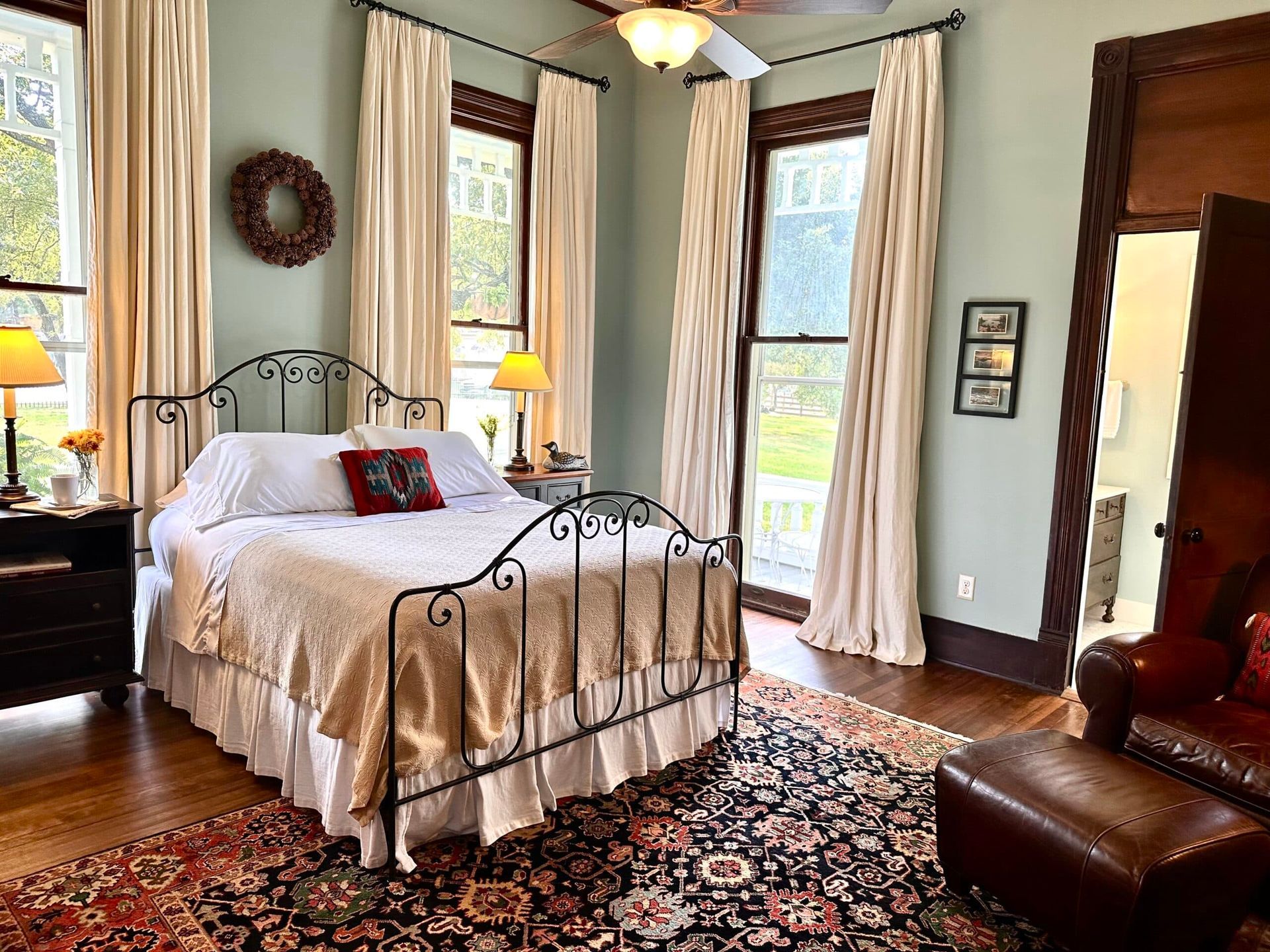 A bedroom with a bed , chair , rug and a ceiling fan.