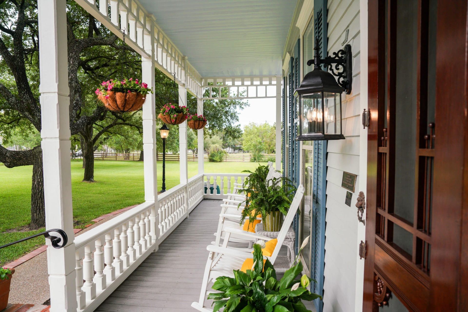 A porch with rocking chairs and potted plants on it.