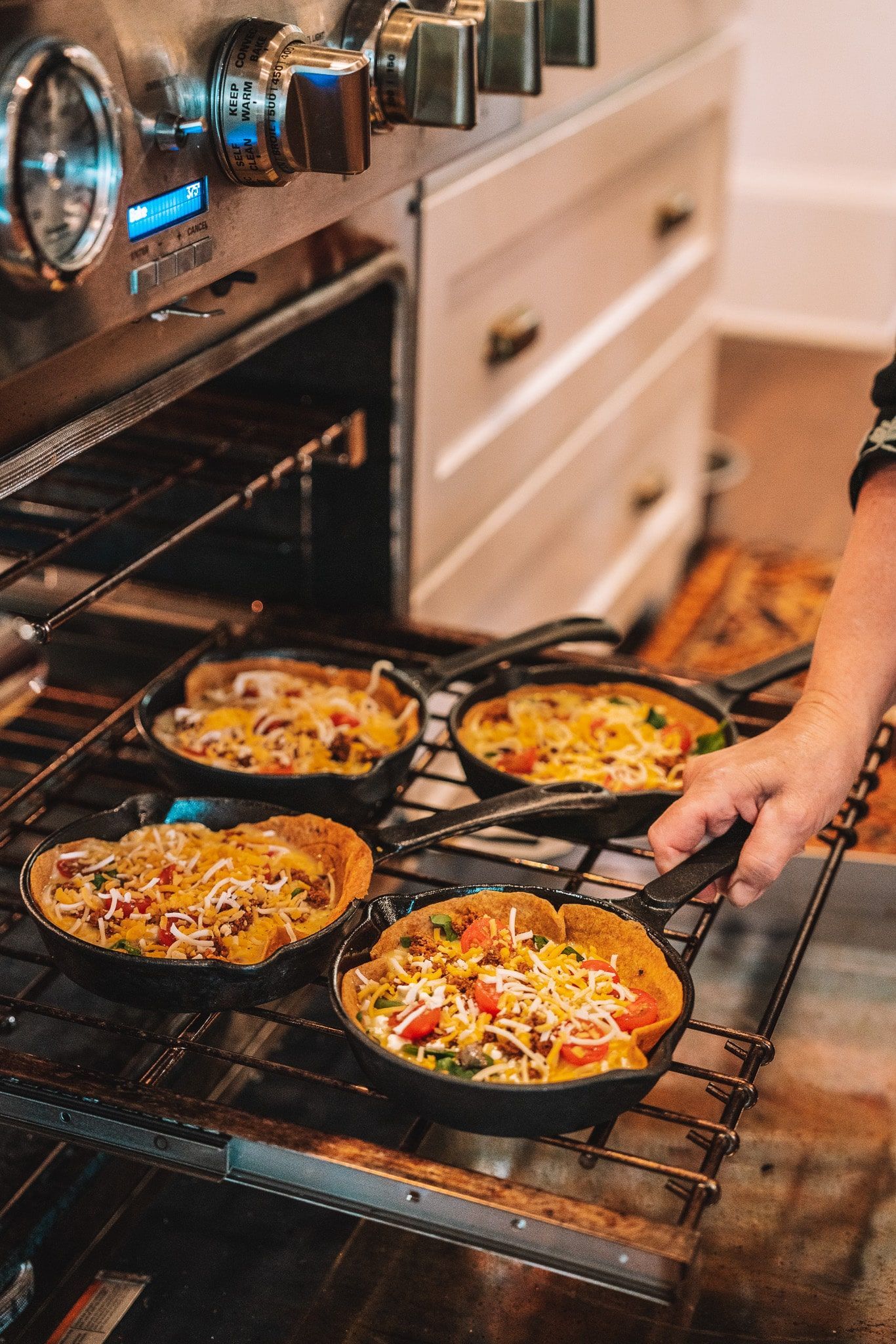 A person is taking a pan of food out of an oven.
