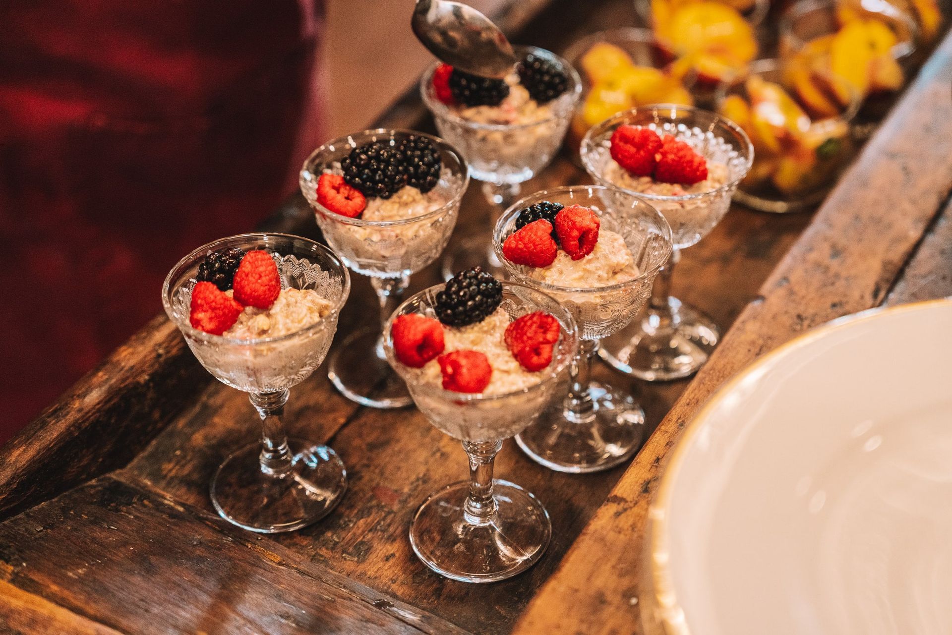A tray of desserts with berries on top of them on a wooden table.