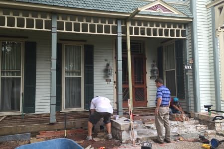 A group of men are working on the porch of a house.