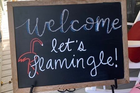 A blackboard with the words `` welcome let 's flamingle '' written on it.