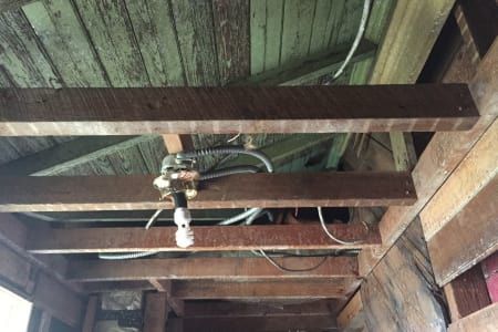 A ceiling with wooden beams and wires hanging from it.
