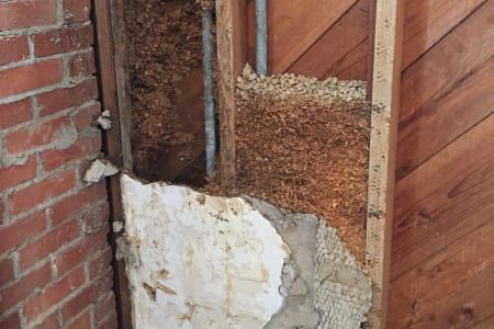 A brick wall with a piece of wood missing from it.