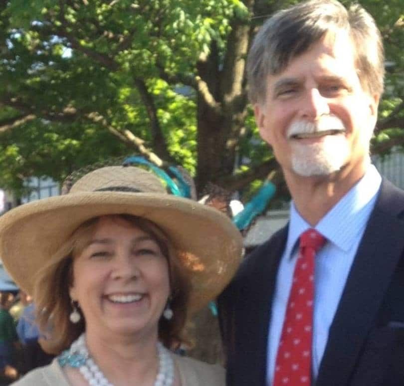 A man and woman are posing for a picture and the woman is wearing a straw hat