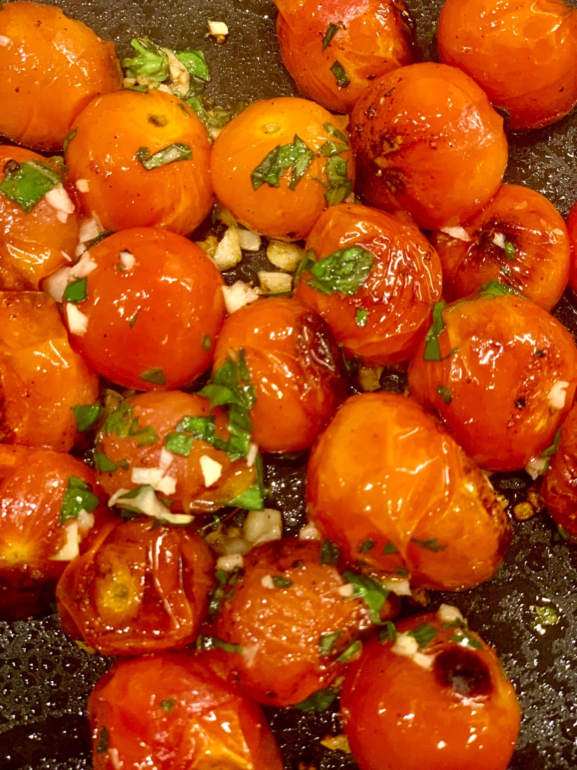 A bunch of tomatoes are being cooked in a pan.