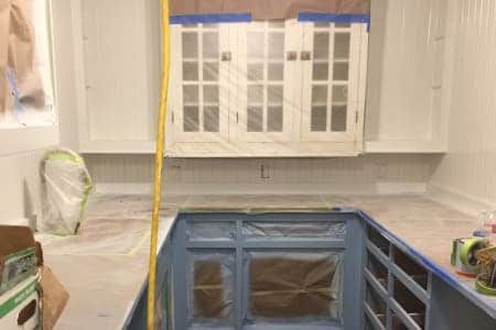 A kitchen with blue cabinets and white cabinets is being painted.