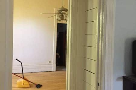 A room with a ceiling fan and a broom on the floor.