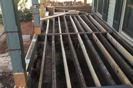 A wooden deck is being built in front of a house