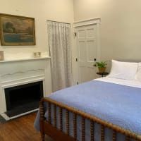 A bedroom with a bed , fireplace and painting on the wall.