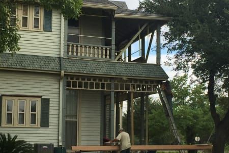 A man is standing in front of a house that is being remodeled.