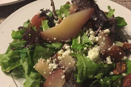 A close up of a salad on a white plate on a table.
