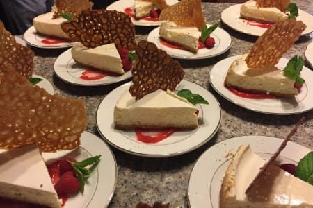 A table topped with plates of cheesecake and raspberries.
