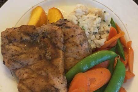 A white plate topped with meat , rice , carrots and peas.