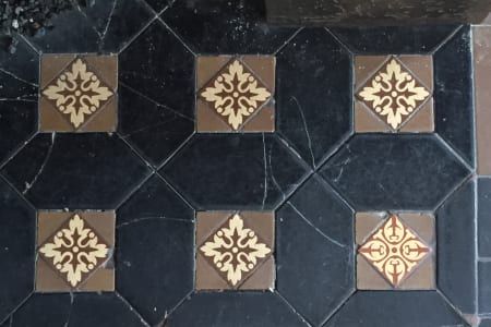 A black and brown tile floor with a floral pattern