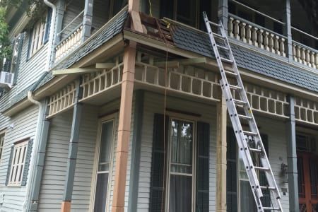 A ladder is hanging from the side of a house.