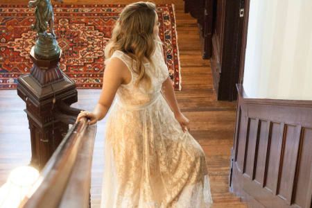A woman in a white dress is walking down a set of stairs.
