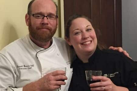 A man and a woman are posing for a picture while holding wine glasses.