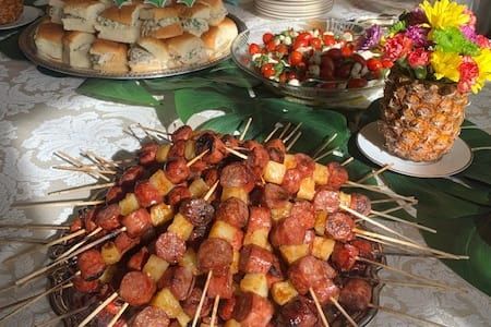 A table topped with a variety of food including skewers of sausage and pineapple.