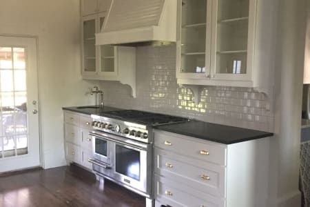 A kitchen with white cabinets , stainless steel appliances , a stove and a sink.