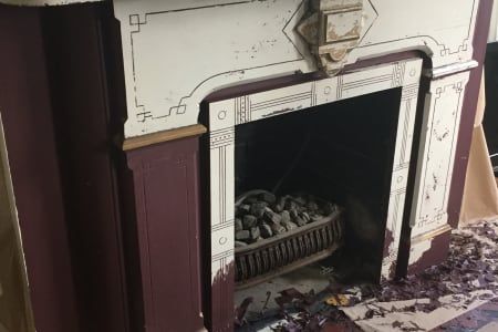 A fireplace with a purple and white mantle is being painted.