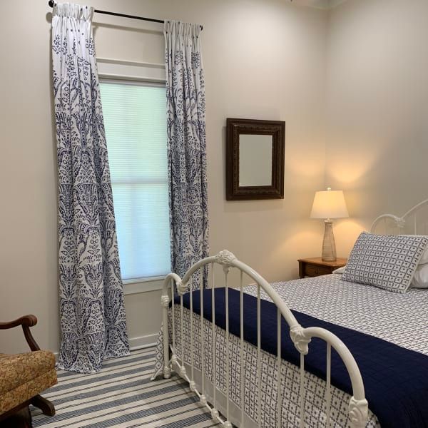 A bedroom with a bed a chair and a mirror