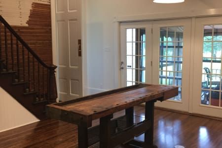 A wooden table is sitting in a room next to a staircase.