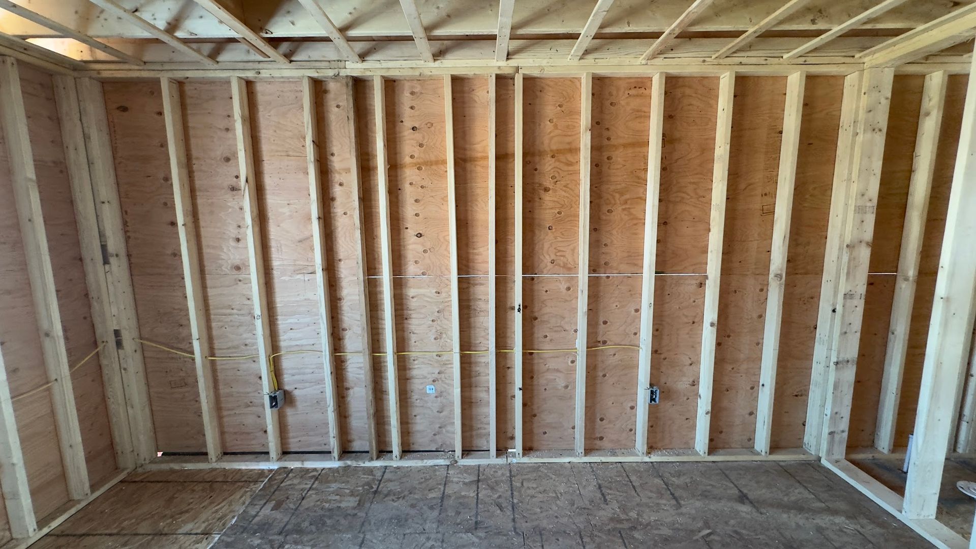 Interior of a room under construction with exposed wooden studs and framing.