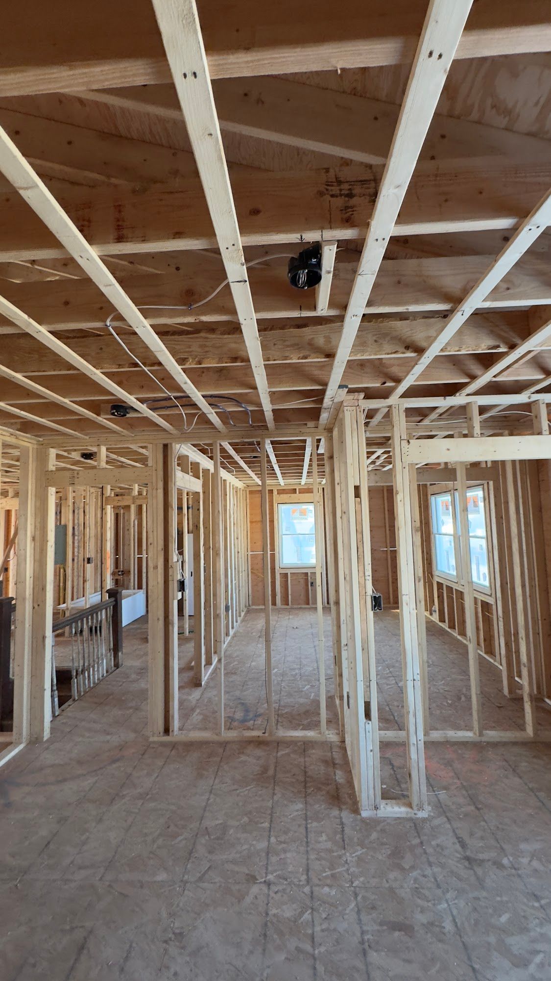 Interior of a house under construction; wooden framing for walls, ceiling, and floor are visible.