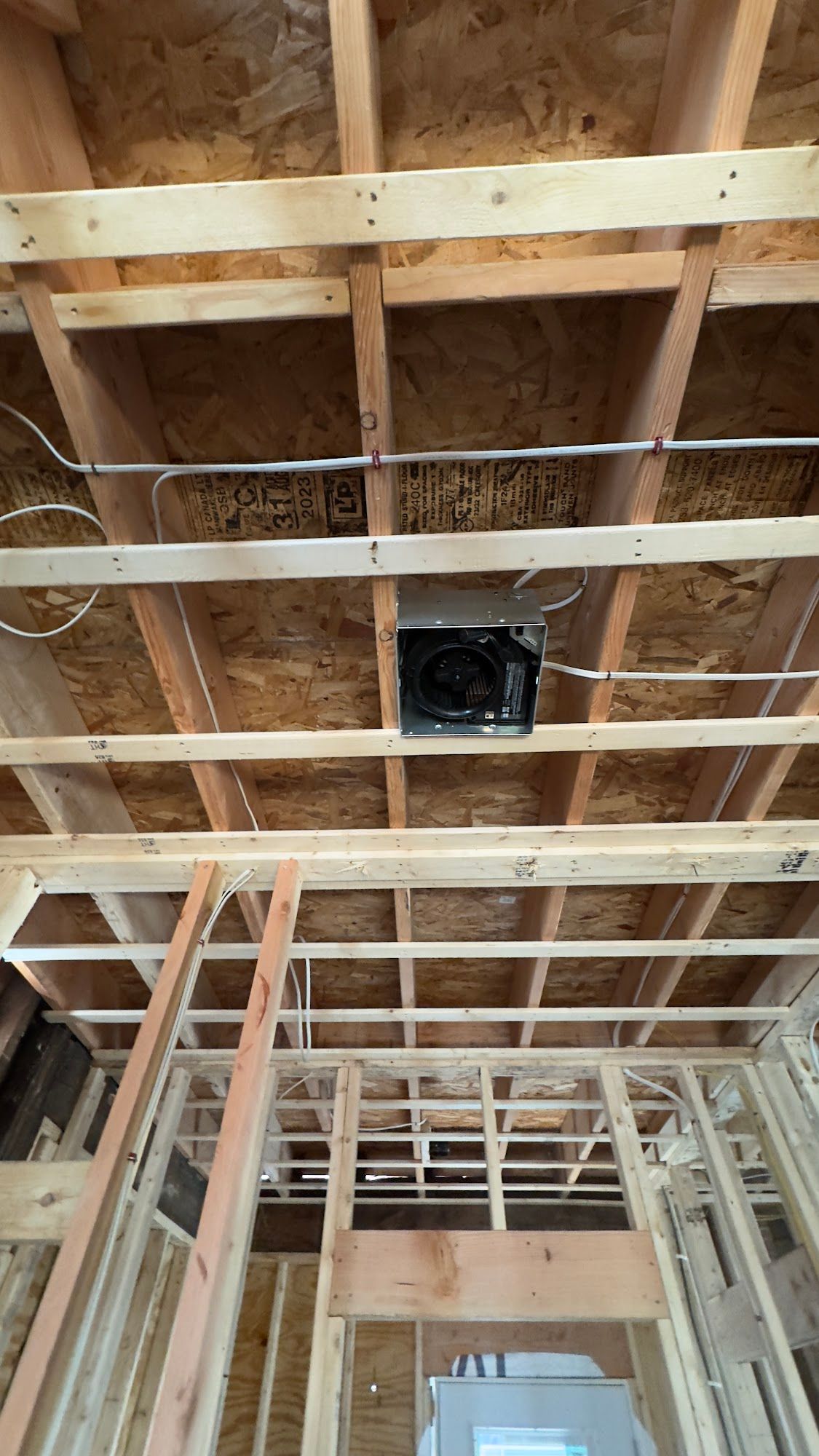 Wooden ceiling frame with a recessed ventilation fan, wiring visible.