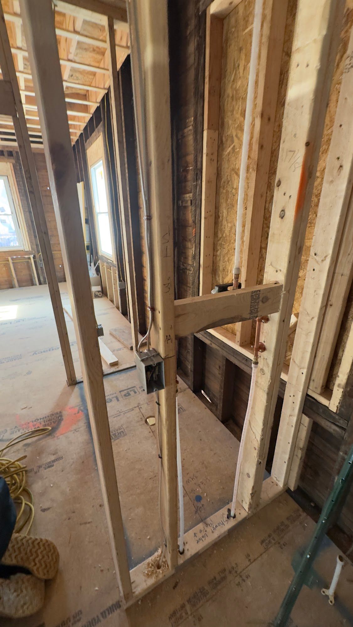 Interior construction: wooden framing of walls, electrical box, and a window in a room under renovation.