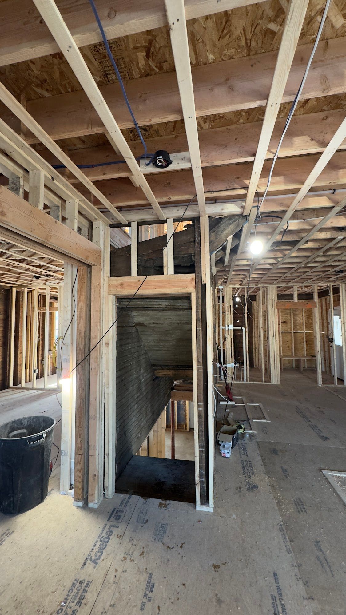 Interior view of a building under construction, showing wooden framing and stairwell.