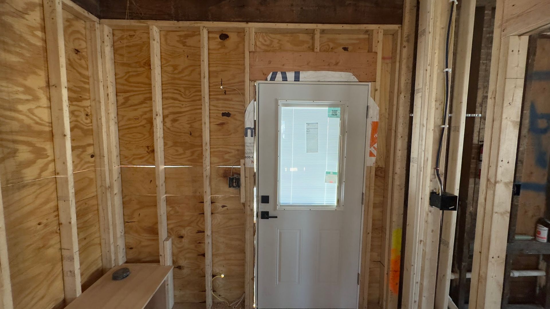 Interior view of a door frame with a door installed, unfinished wooden walls.
