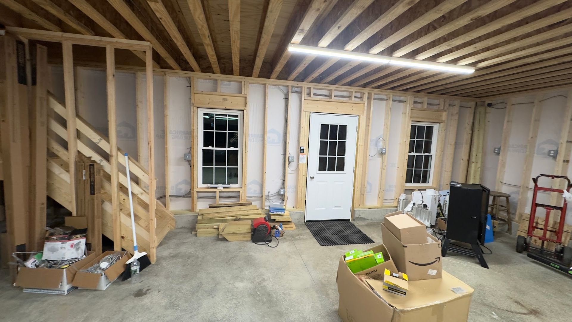 Interior of a partially constructed building. Wooden framing, a staircase, windows, door, and exposed.
