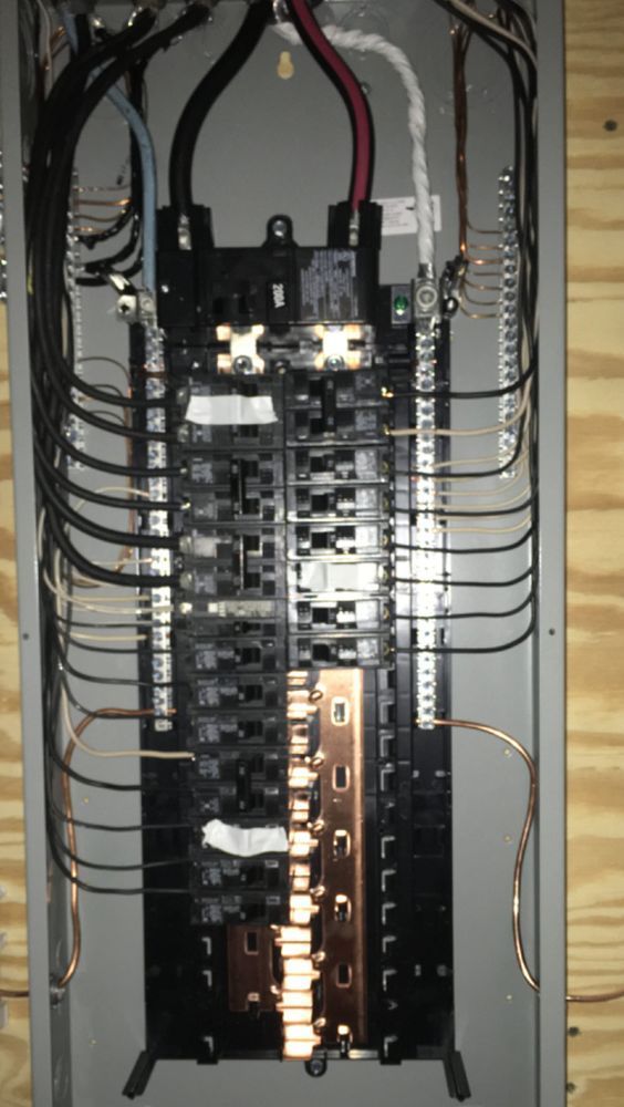 Electrical circuit breaker panel with wires connected, against a wooden background.