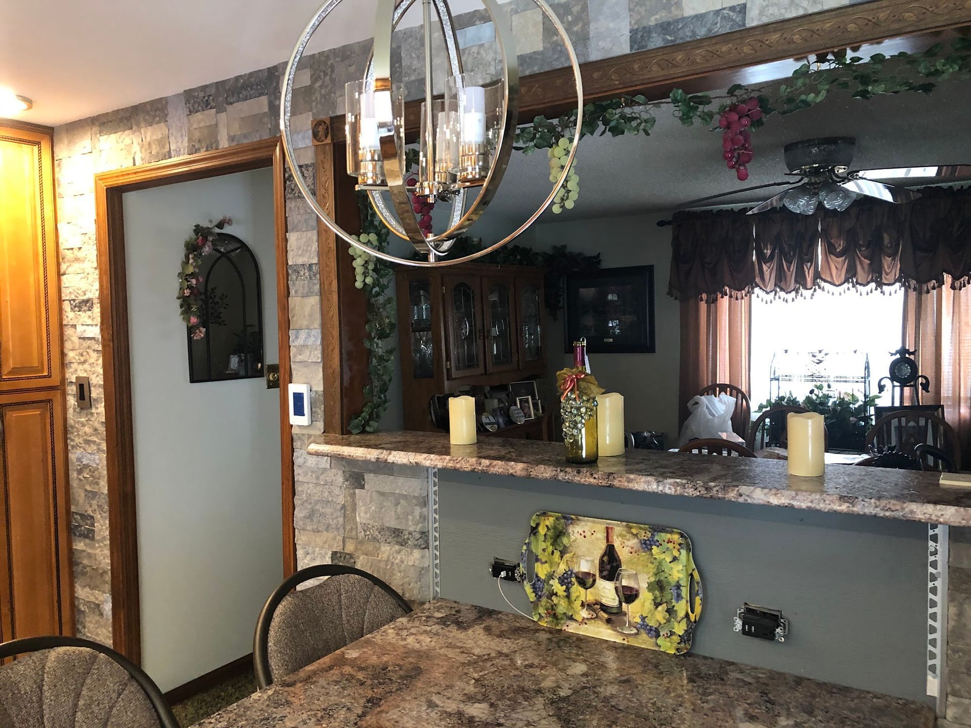 Dining room with stone wall, chandelier, and a countertop, with decorative items.