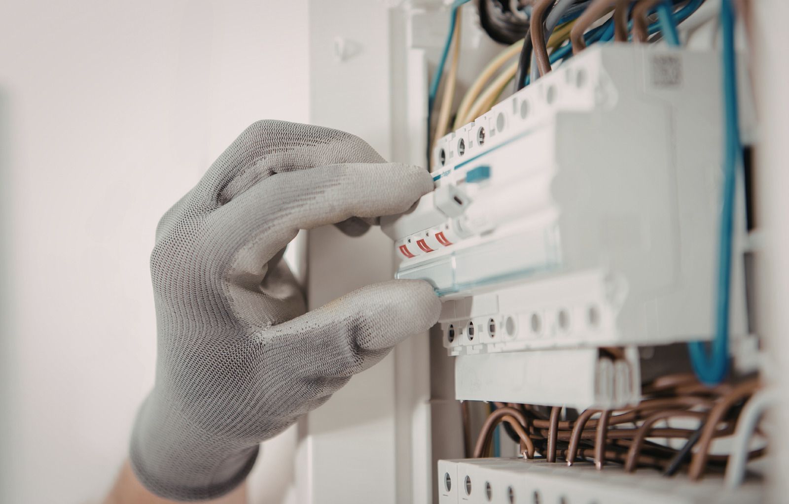 Two gray electrical panels with conduit pipes, mounted on a gray wall in a utility room.