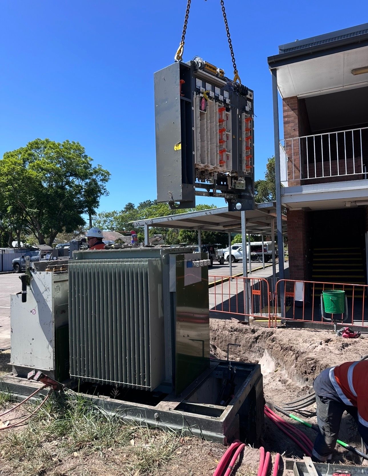 Construction site with an upright electrical cabinet beside a house under renovation.