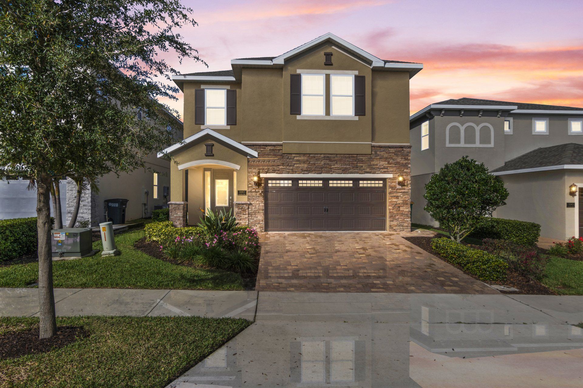 A large house with a garage and a sunset in the background