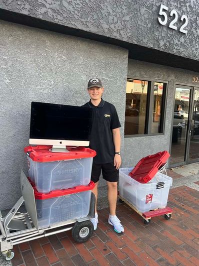Person standing by stacked carts with red-topped bins outside storefront 522